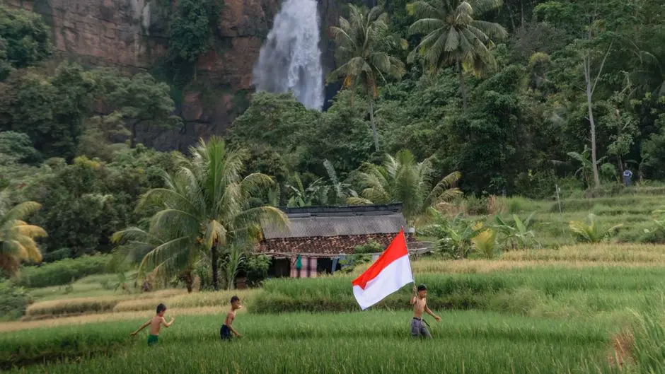 Anak-anak bermain di air terjun dangkal dengan latar hijau Aceh